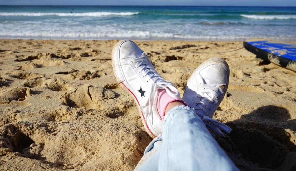 an artistic shot of a student's shoes on a beach in Sydney