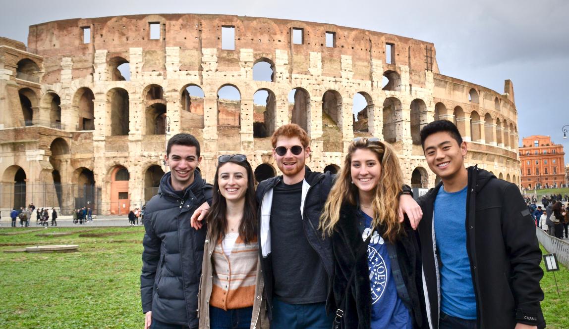 a group of students posing for a photo in front of the Colosseum