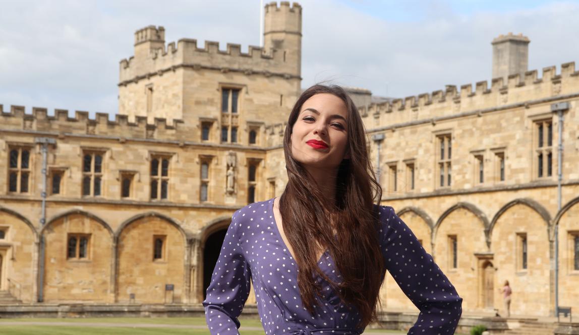 a student poses for a photo in front of Oxford University