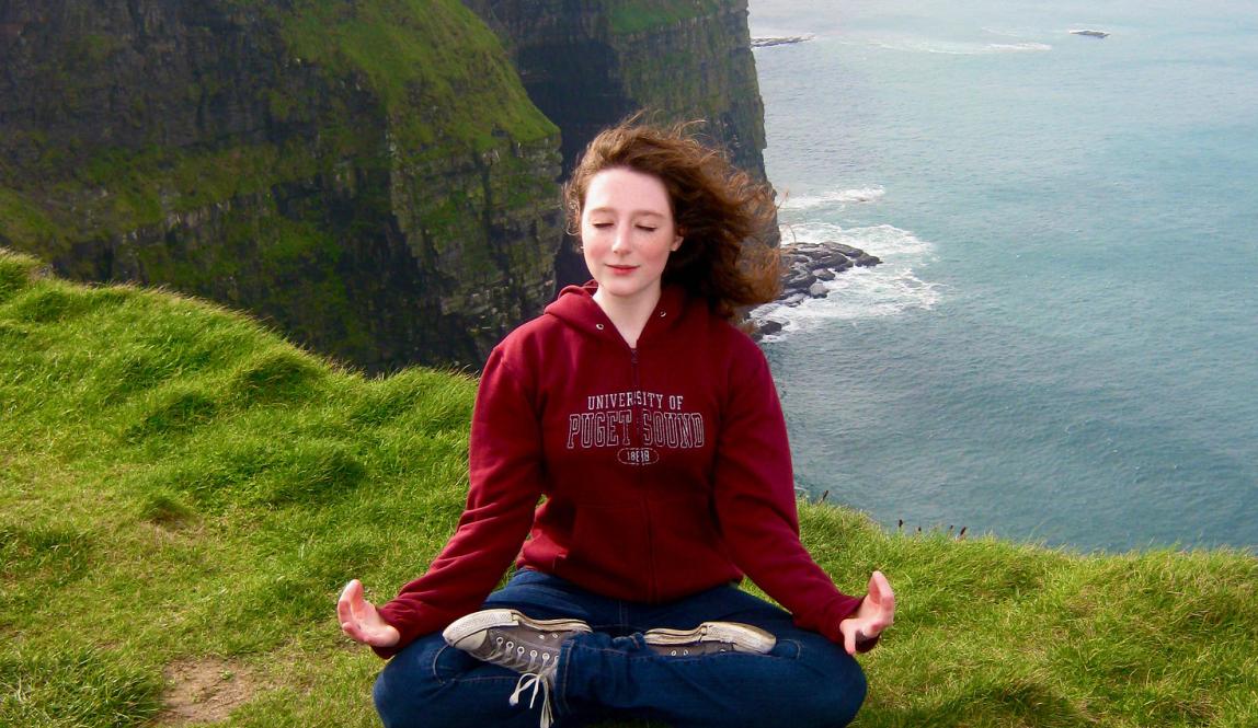 a student meditating near the Cliffs of Moher in Ireland