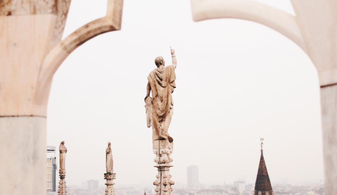 an artistic shot of a statue atop Duomo di Milano