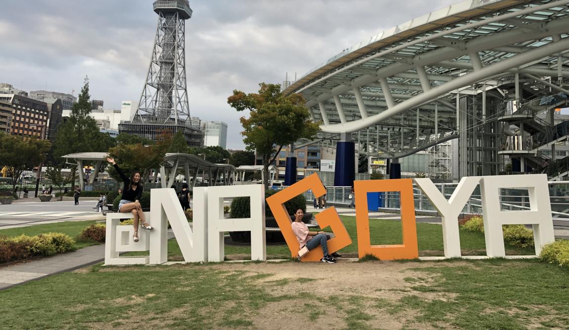 a student poses for a photo while sitting inside the Nagoya sign
