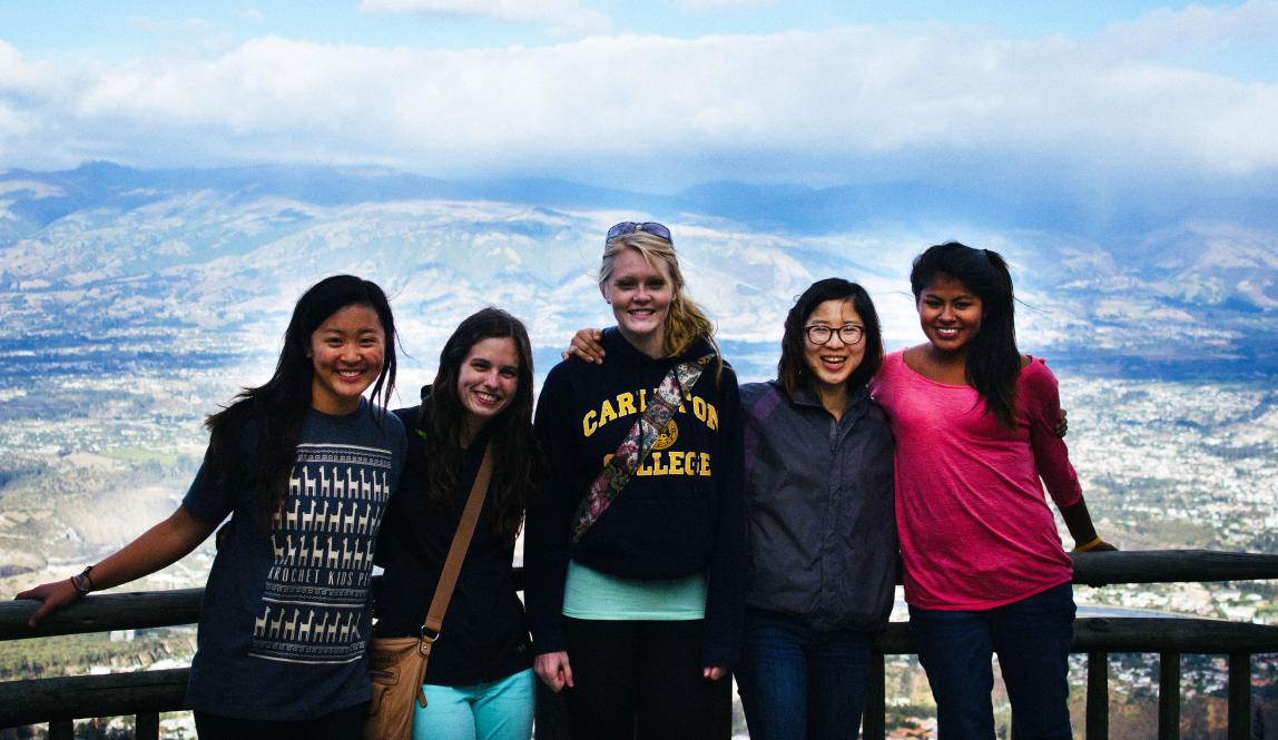 a group of students pose for a photo from atop the mountains in Quito with a backdrop of the city