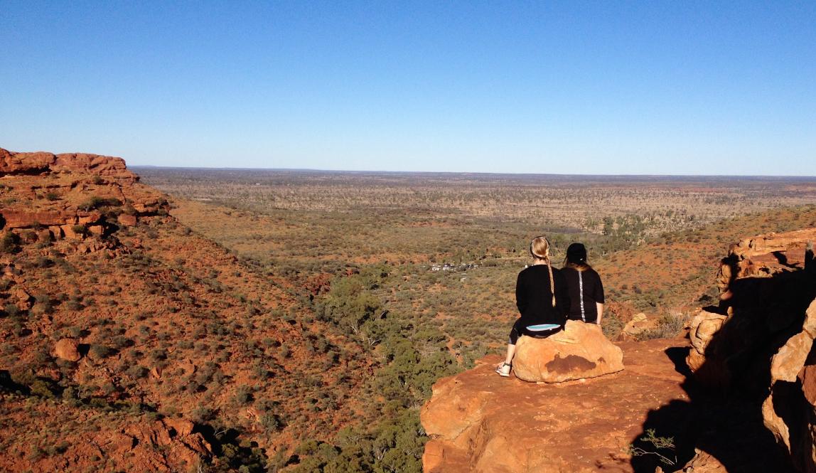 students sitting on a cliff looking out over the outback