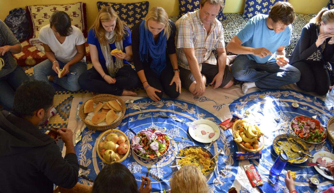 a group of people in Rabat sitting on the floor to eat dinner