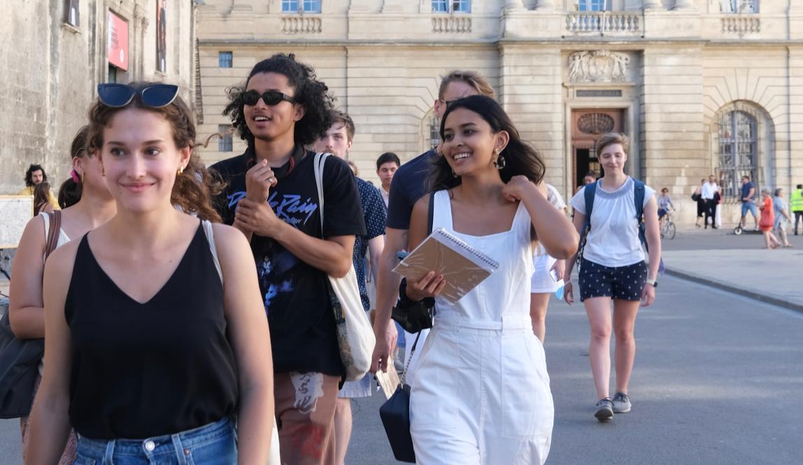a candid photo of students walking outside in front of French architecture and a French flag
