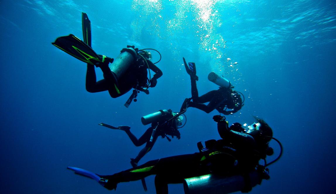 four students scuba diving in Galápagos