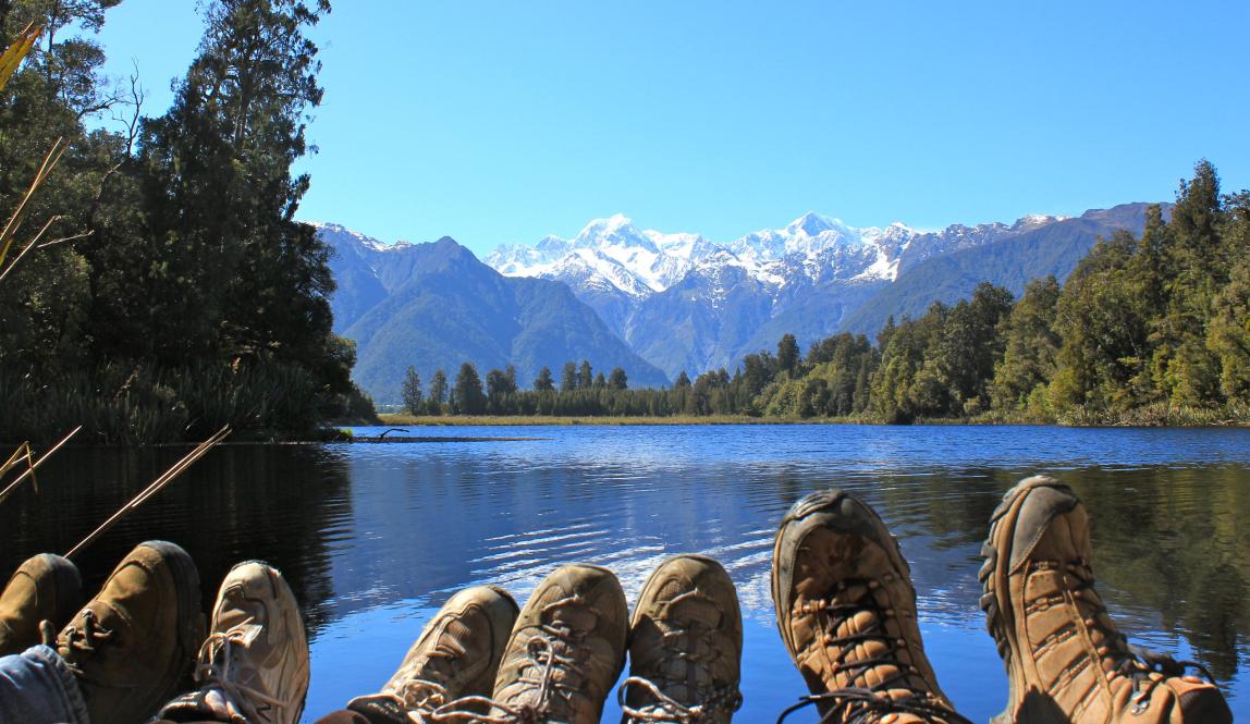 a photo of students hiking boots in front of New Zealand mountains
