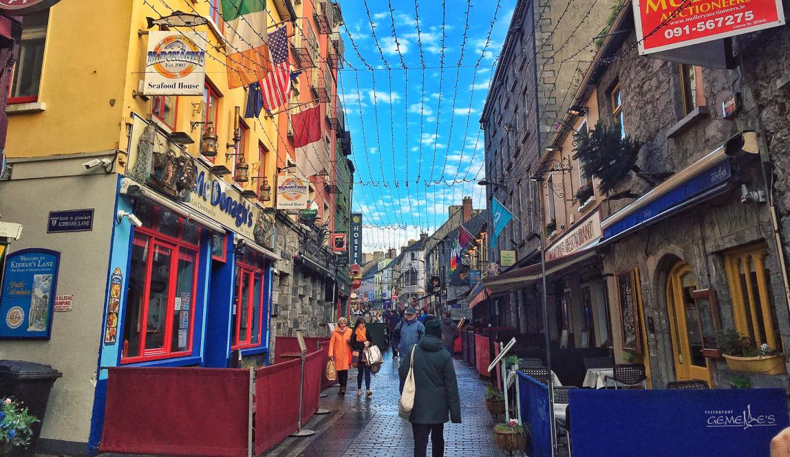 People walk down colorful Quay Street in Galway, Ireland. 