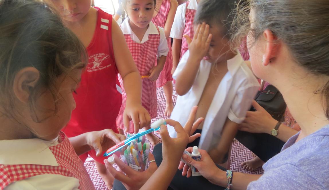 a student intern passing out pens to elementary school students