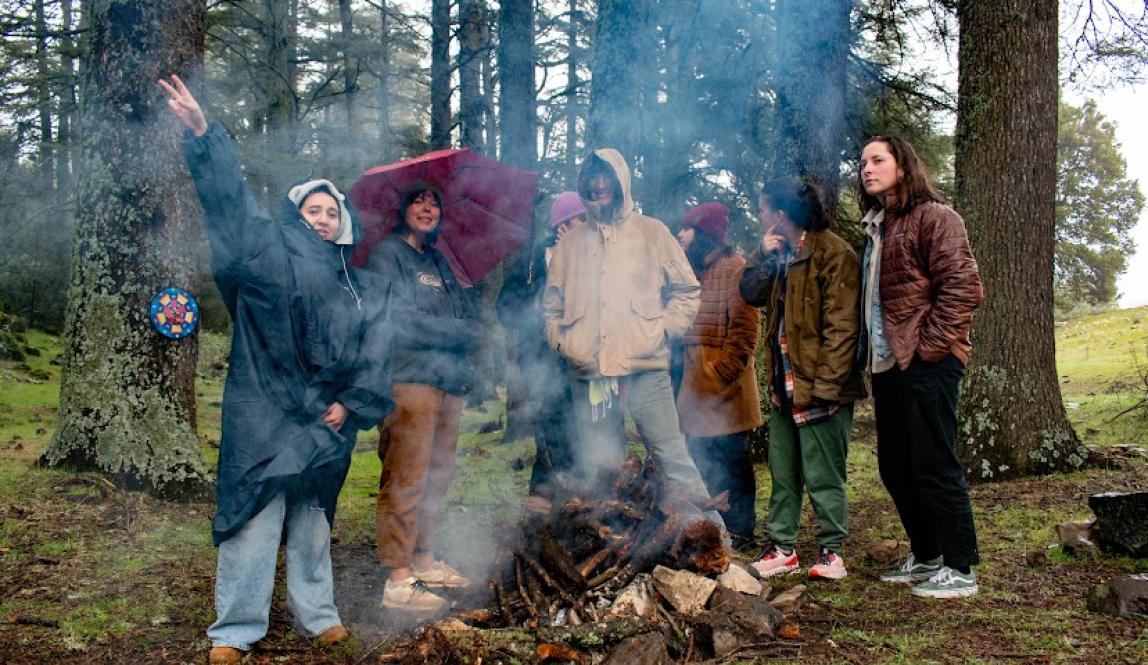 A group students around a smokey fire