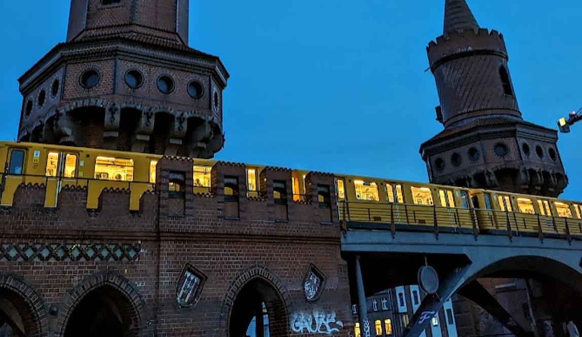 Subway train lit up at night on top of red brick bridge with two towers on each side of it