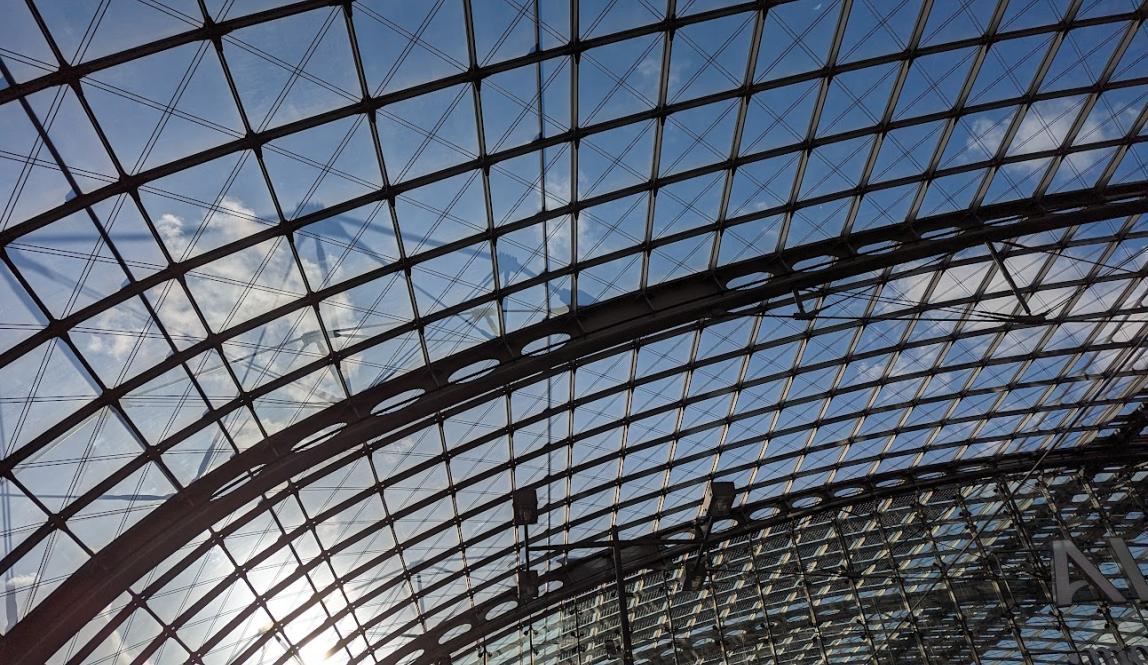 Arching glass ceiling with blue sky and clouds