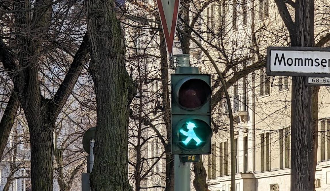 Street light in East Berlin with green Ampelmann, a small green man wearing a hat and walking