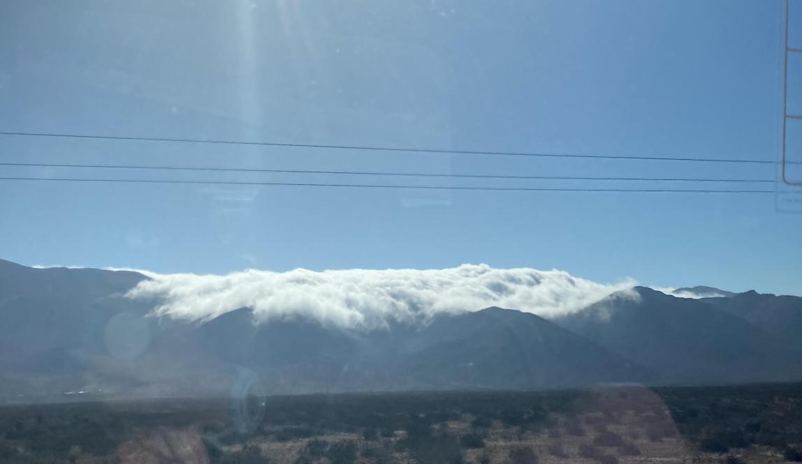 Snowy mountain and slightly in bloom desert field as seen through a van window
