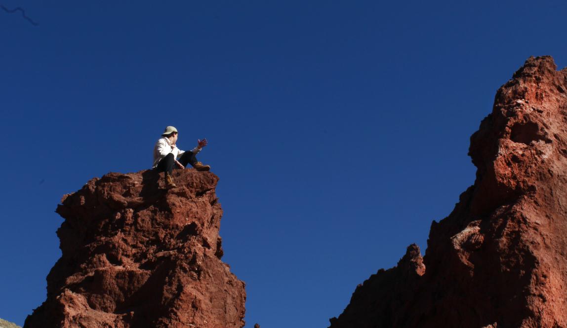 A students sits on the top of a rock.