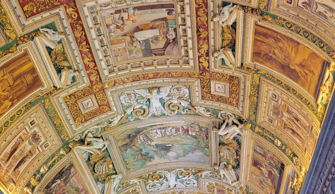 Shown is the golden ceiling of a Vatican Museum clad with paintings