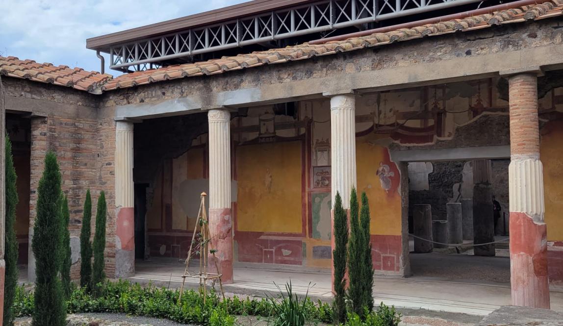 Shown is the garden of a ruined courtyard in Pompeii, boasting an impressive fresco