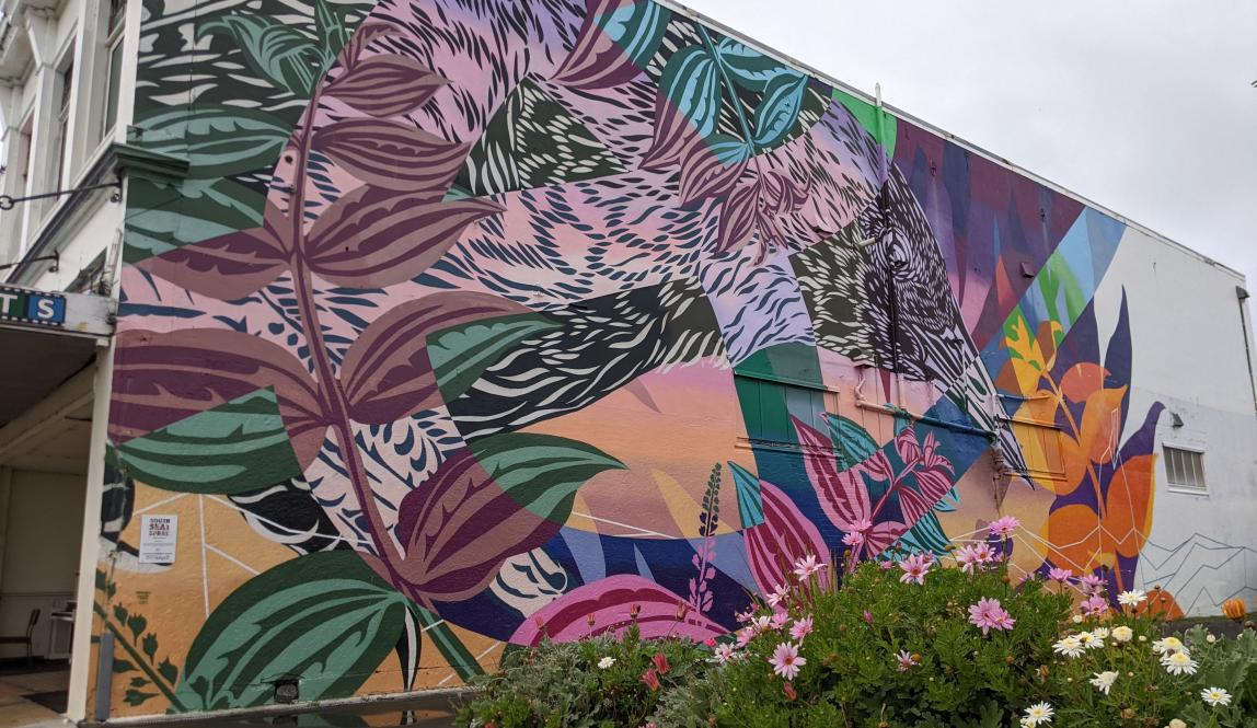 Colorful mural of a bird and some foliage on the side of a building