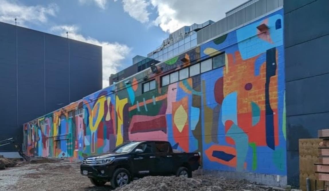 A colorful, abstract mural with a truck parked in front of it