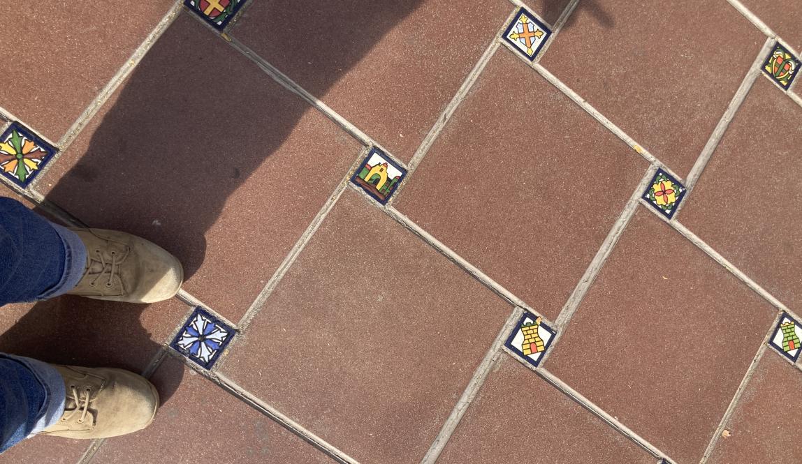 Red clay tiles with small mosaic images serve as the walkway in Mendoza’s Plaza España