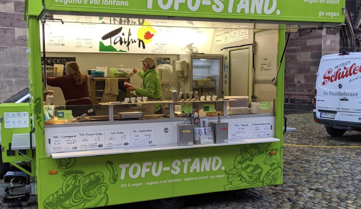 Lime green food stand with silhouettes of leaves on it that says Tofu-Stand 