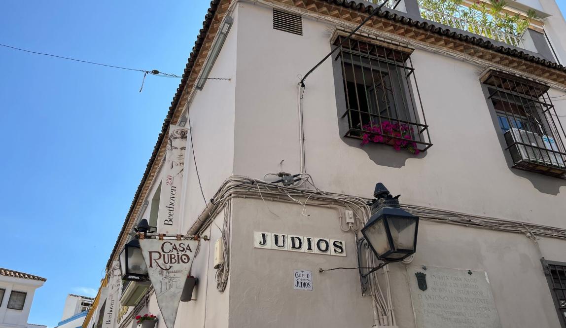 White sign that says Judios on a white building in the Jewish quarter of Cordoba