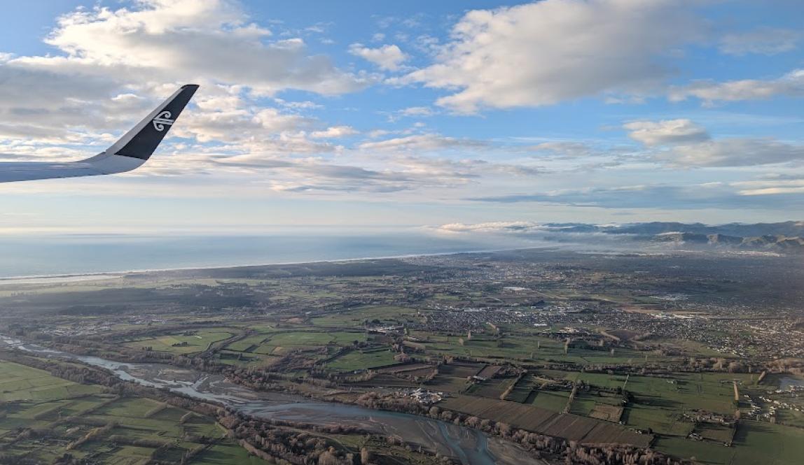 View from a plane over the city of Christchurch with the ocean and some clouds in the distance