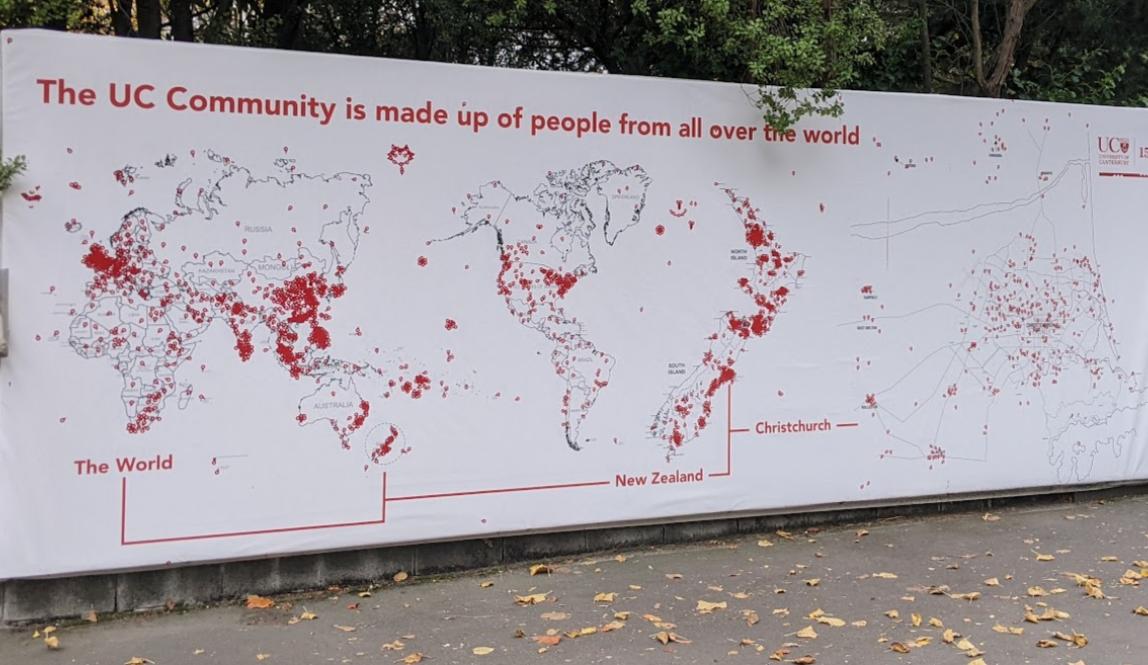 A large display featuring a map of the world with red stickers placed on where people at UC are from