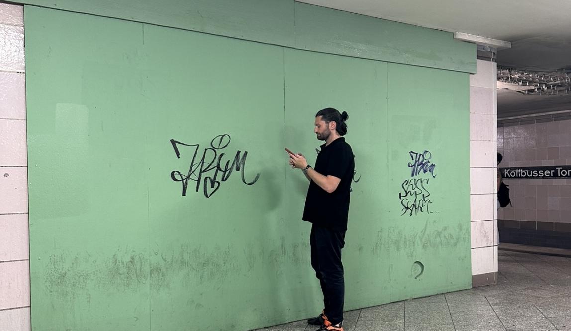 A man in black in front of a brightly colored u-bahn wall