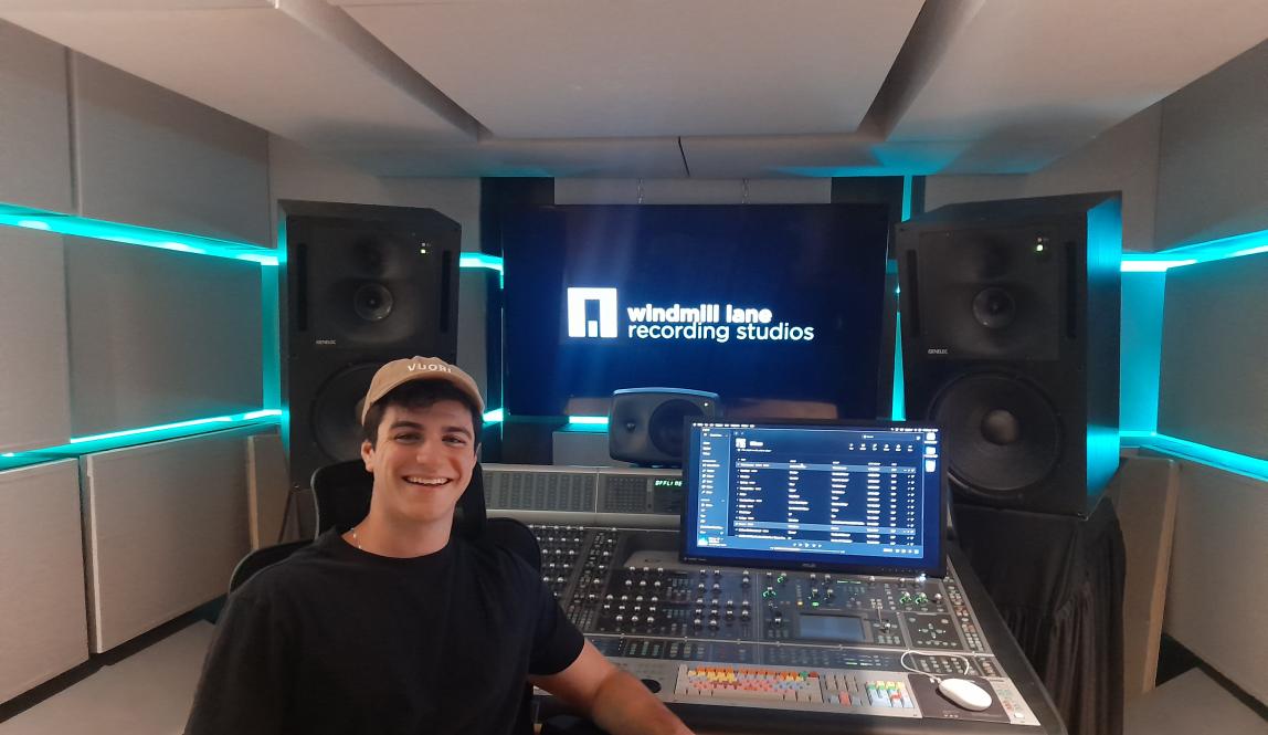 student smiling with hat on in front of audio visual equipment