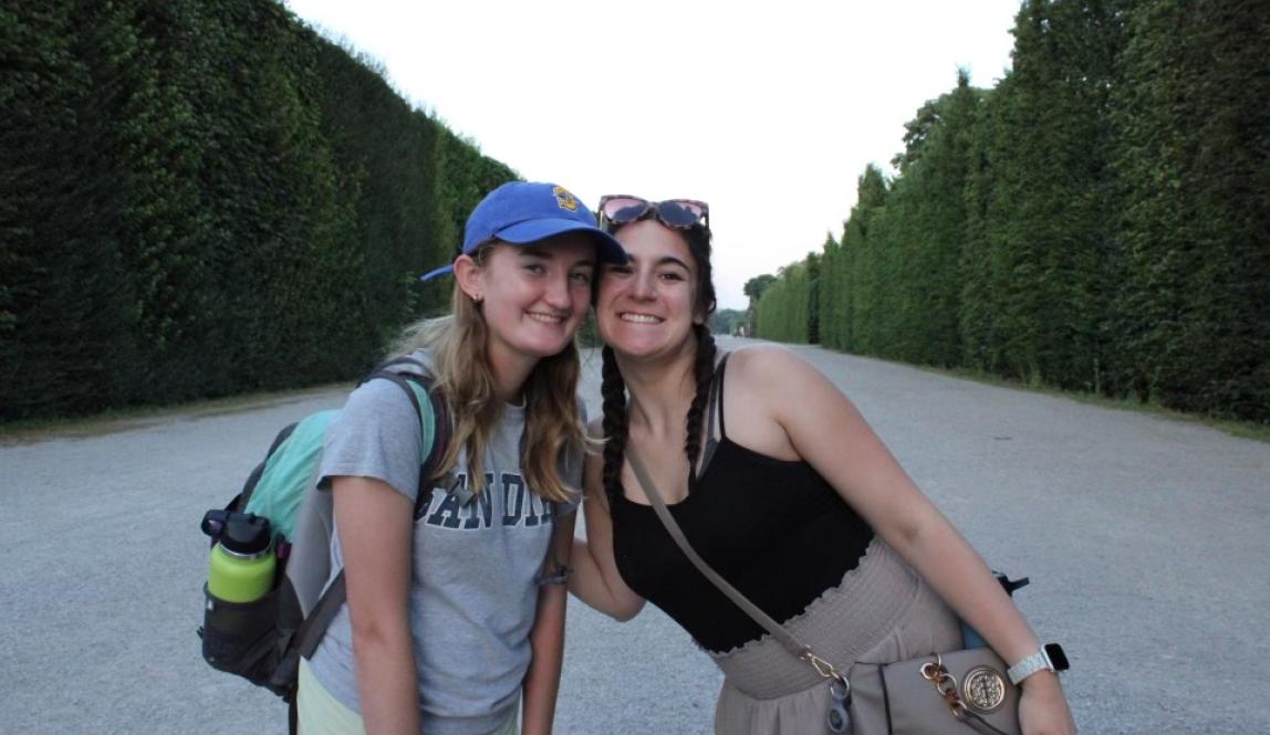 Two girls leaning in to smile in front of the gardens at Schönbrunn