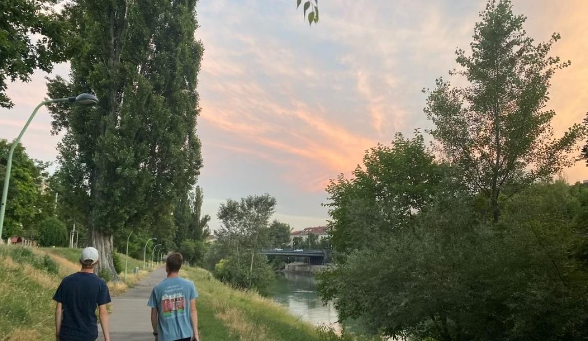 Two guys walking along the river at sunset