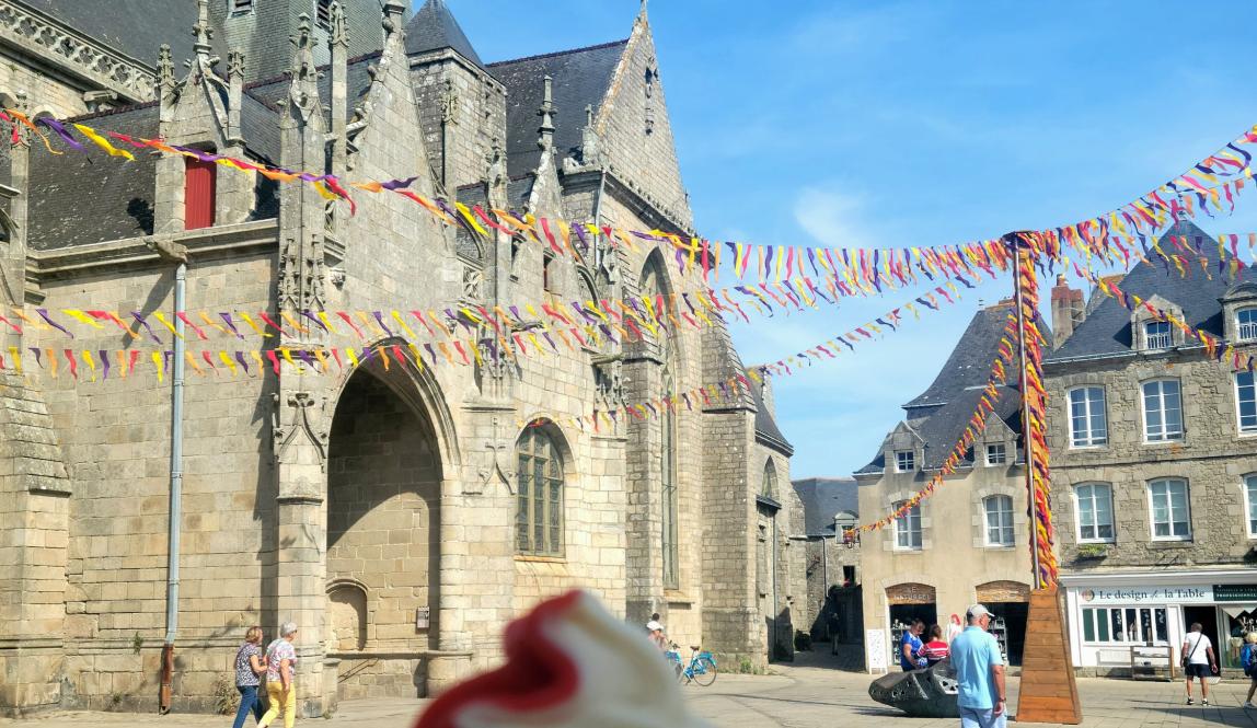 My strawberry vanilla ice cream cone in front of the center in the town which shows the Church and colorful decorations coming from the middle of the center.