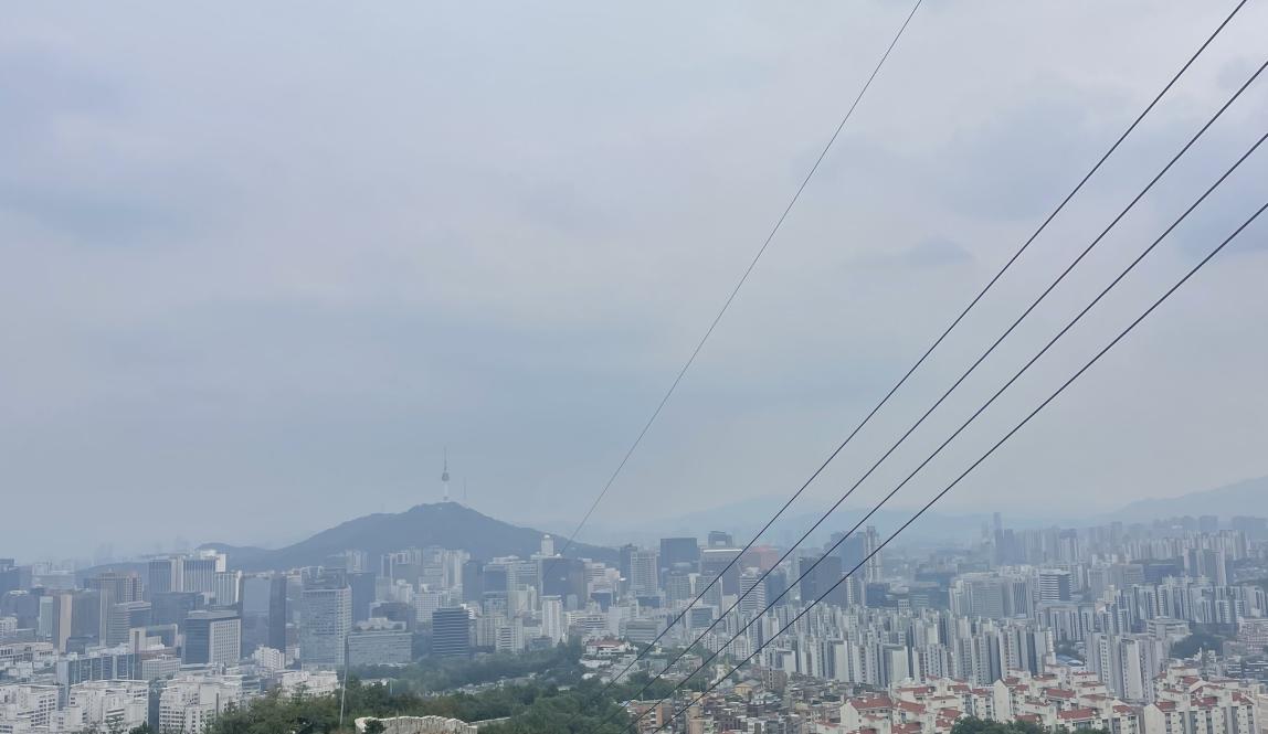 Image of Seoul fortress wall, forested area, and city skyline 