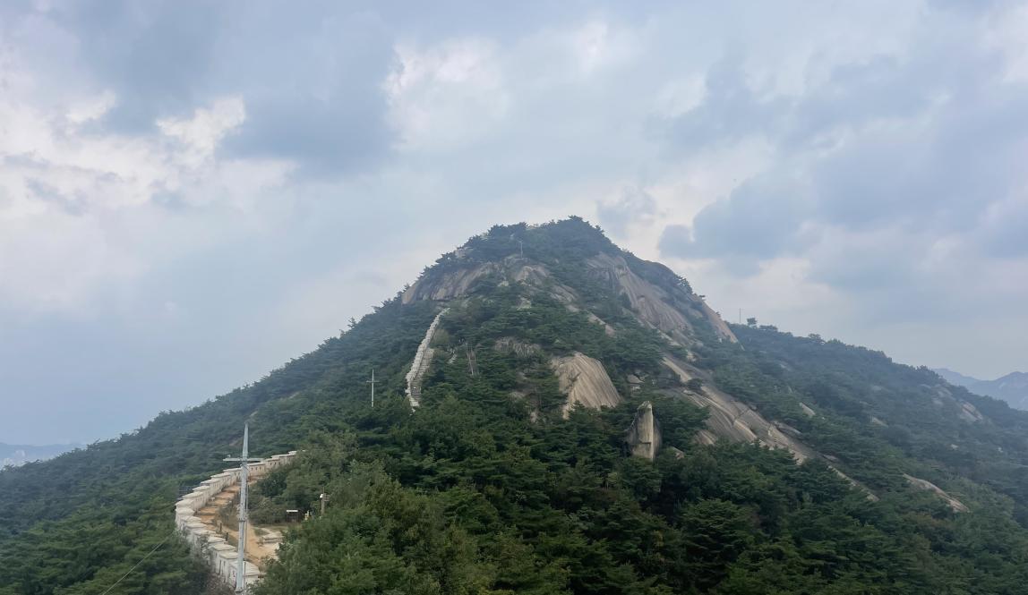 Image of mountain peak with trail and fortress wall 