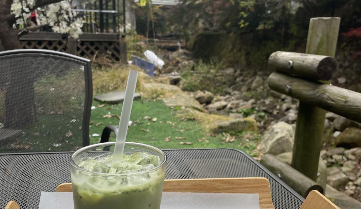 Image of matcha latte and pastry with river and trees in the background 