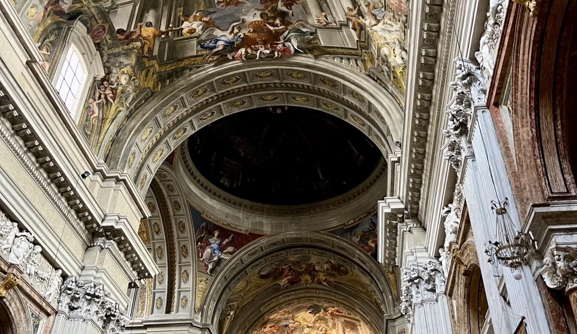 Picture of the ornate paintings and carvings on the ceiling of a church in Rome