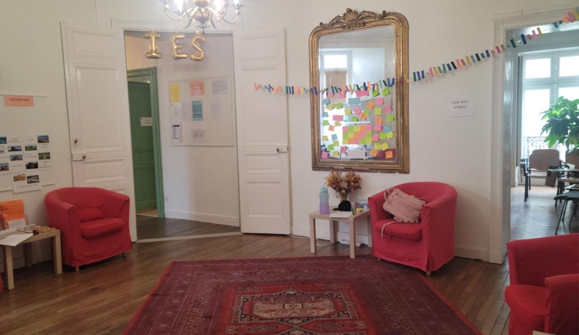 A foyer with access to a hallway and classroom decorated with streamers, couches, and a mirror. 