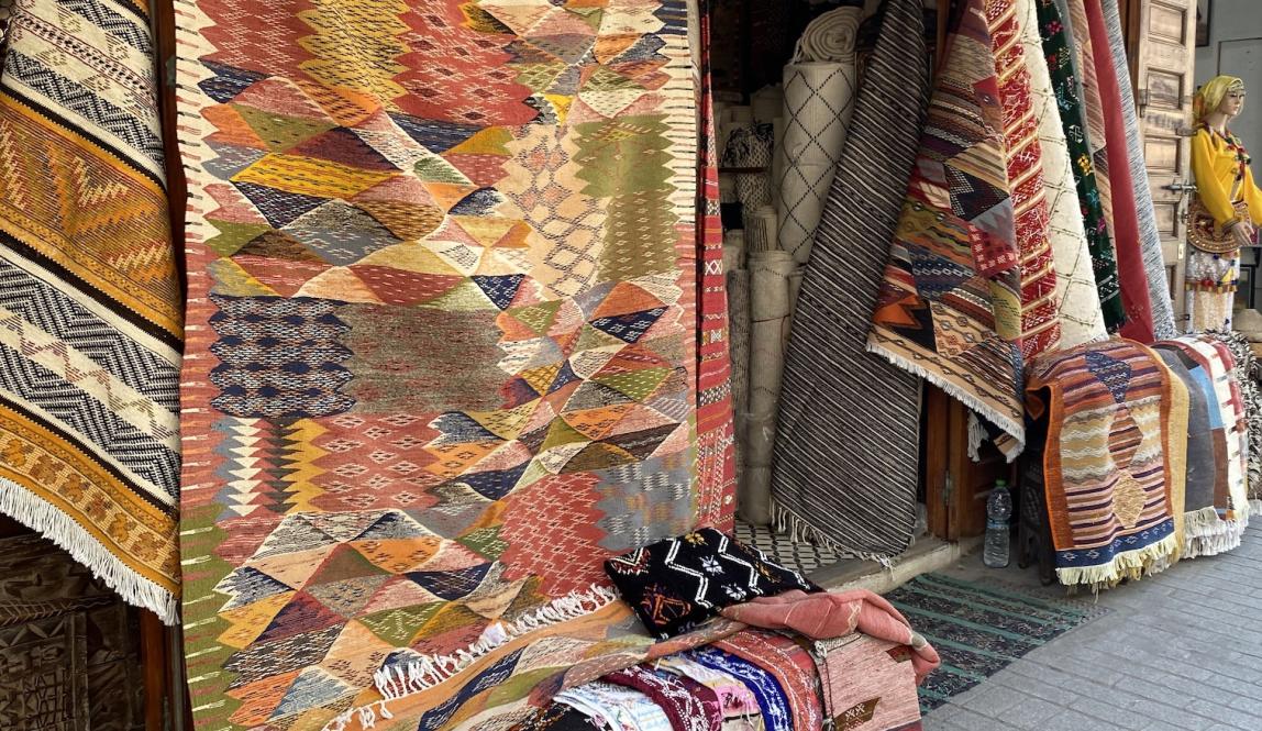 A street with colorful, patterned rugs hanging outside a store