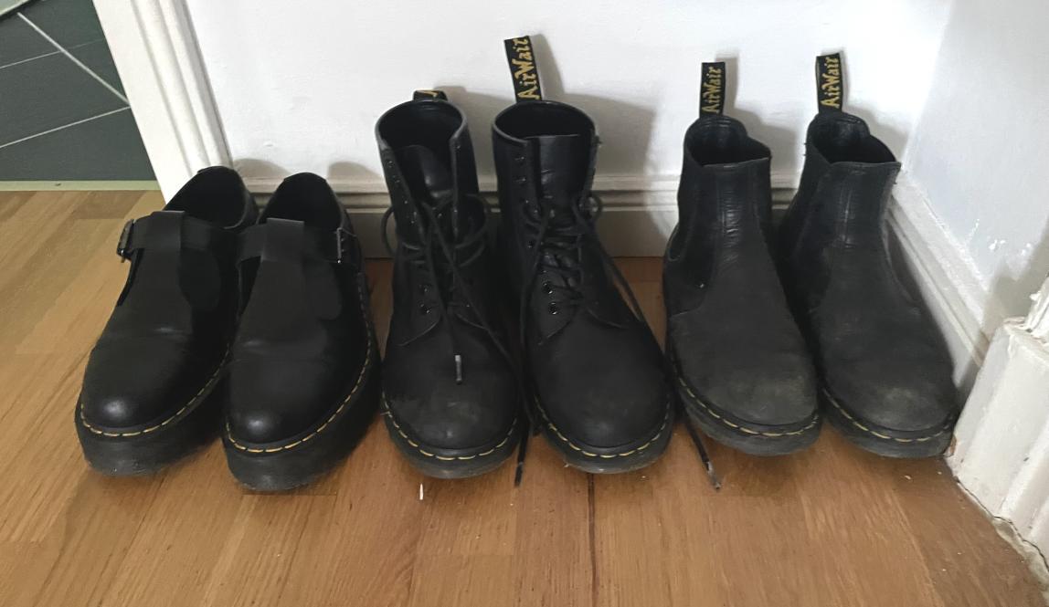 3 different pairs of black boots lined up against the wall
