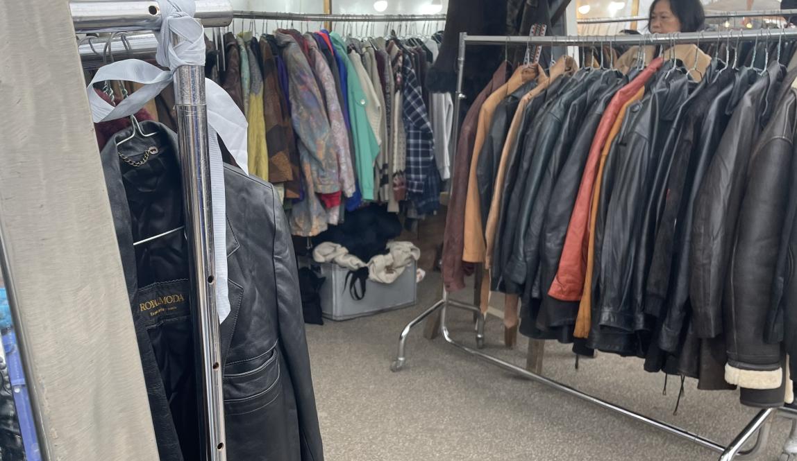 Multiple racks of different jackets at an outdoor flea market