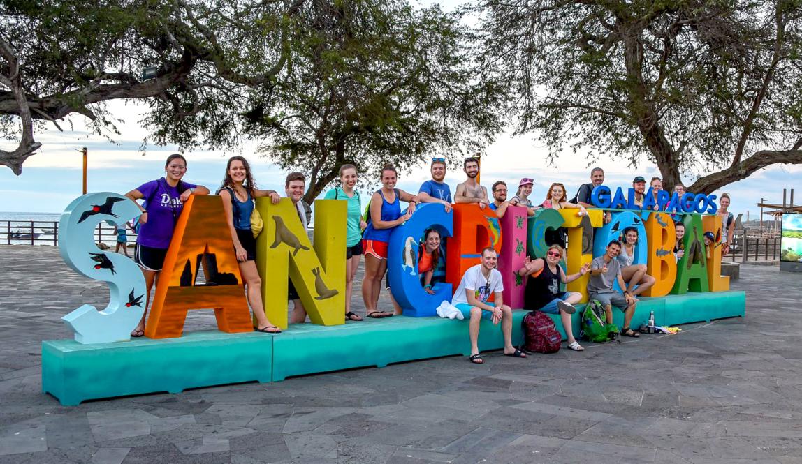 a cohort of students pose for a photo with the San Cristobal Galápagos sign