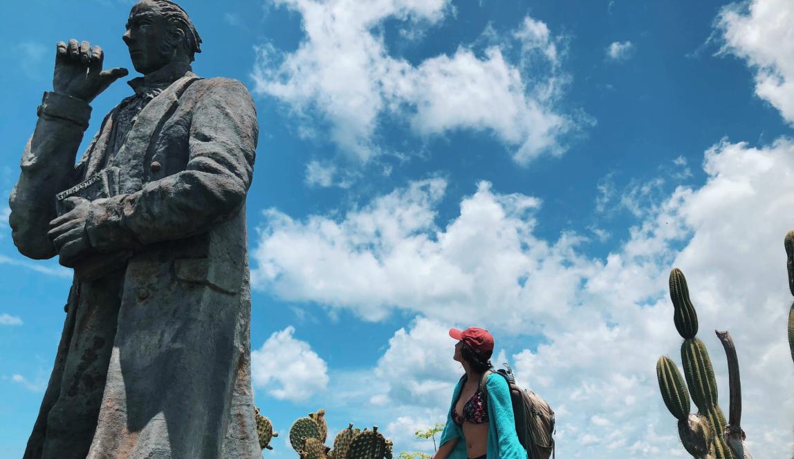a student staring up at a giant statue of Charles Darwin