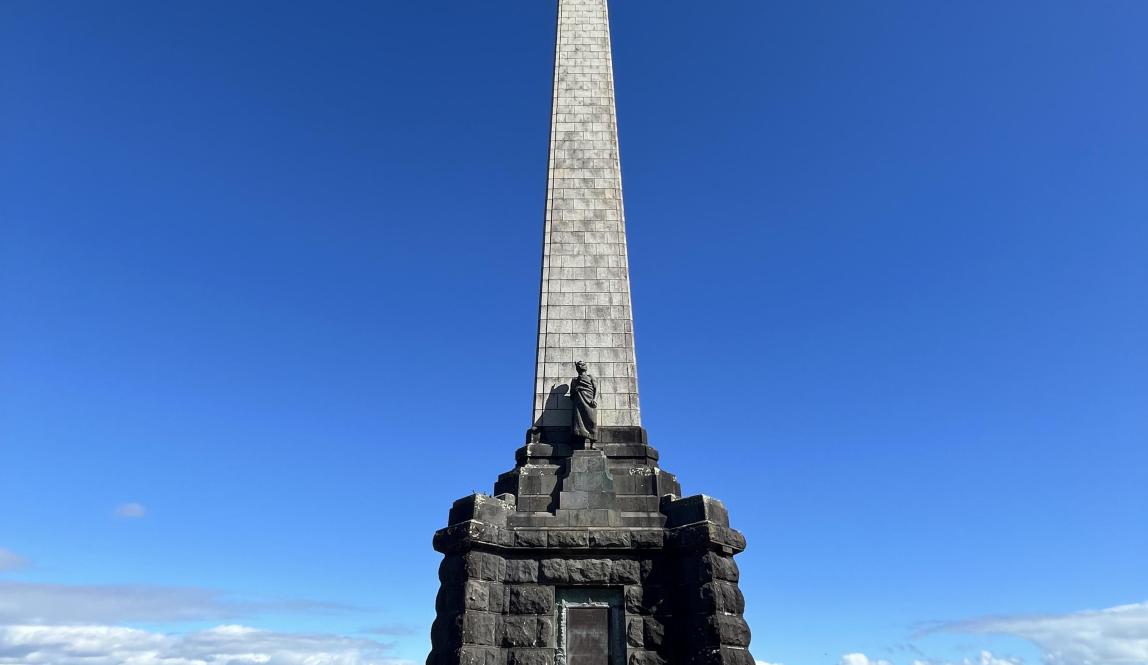 A 30 m tall monument surrounded by pavement.