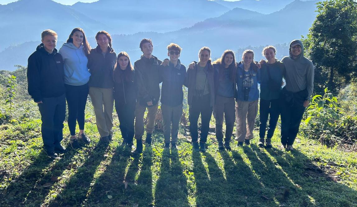 Group of people standing together with a background of mountains. 