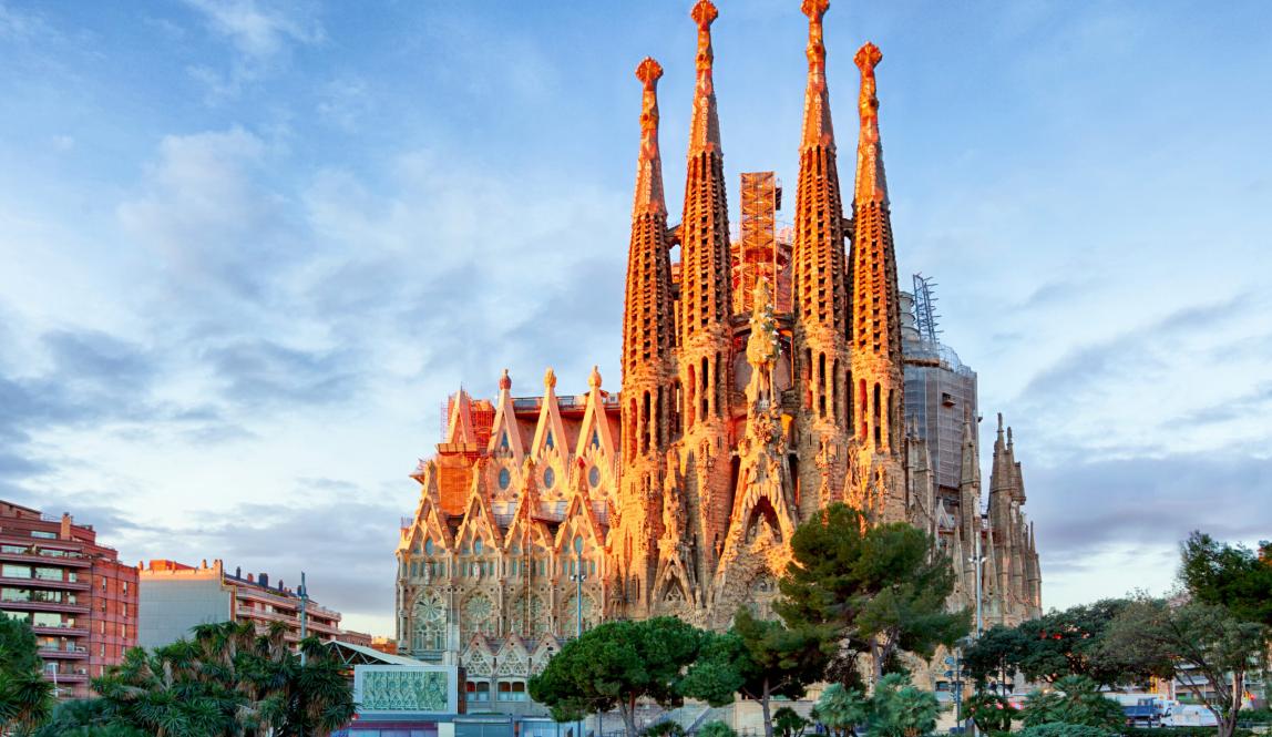 The iconic Sagrada Familia in Barcelona, bathed in golden light, with its towering spires and intricate architecture.