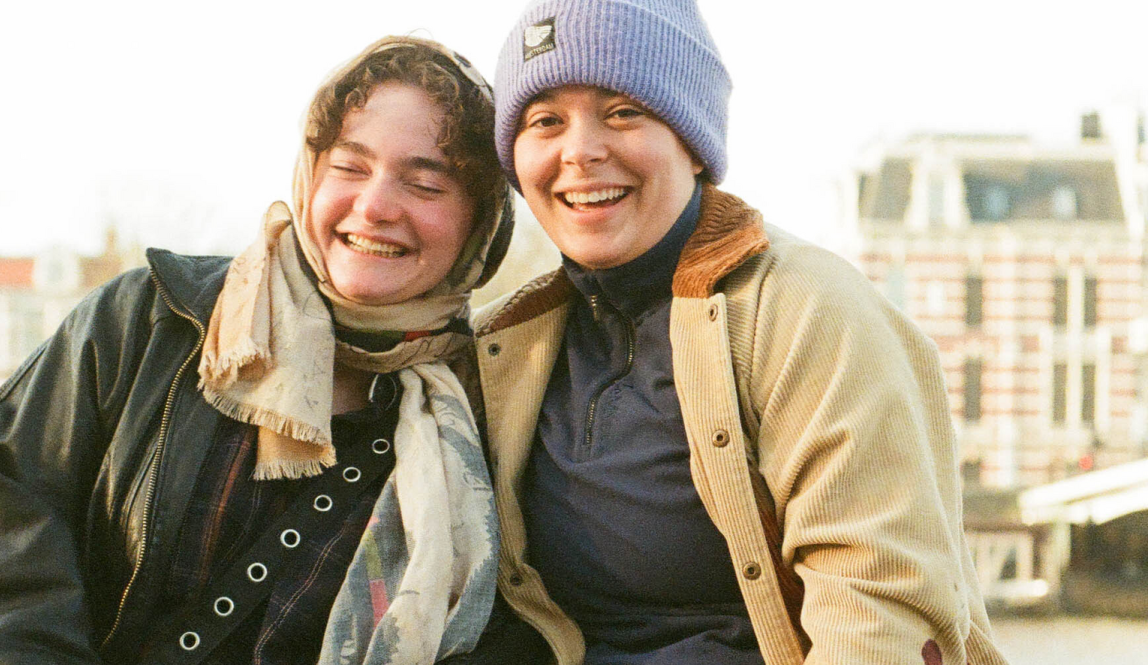 Two students sitting by the amstel in Amsterdam