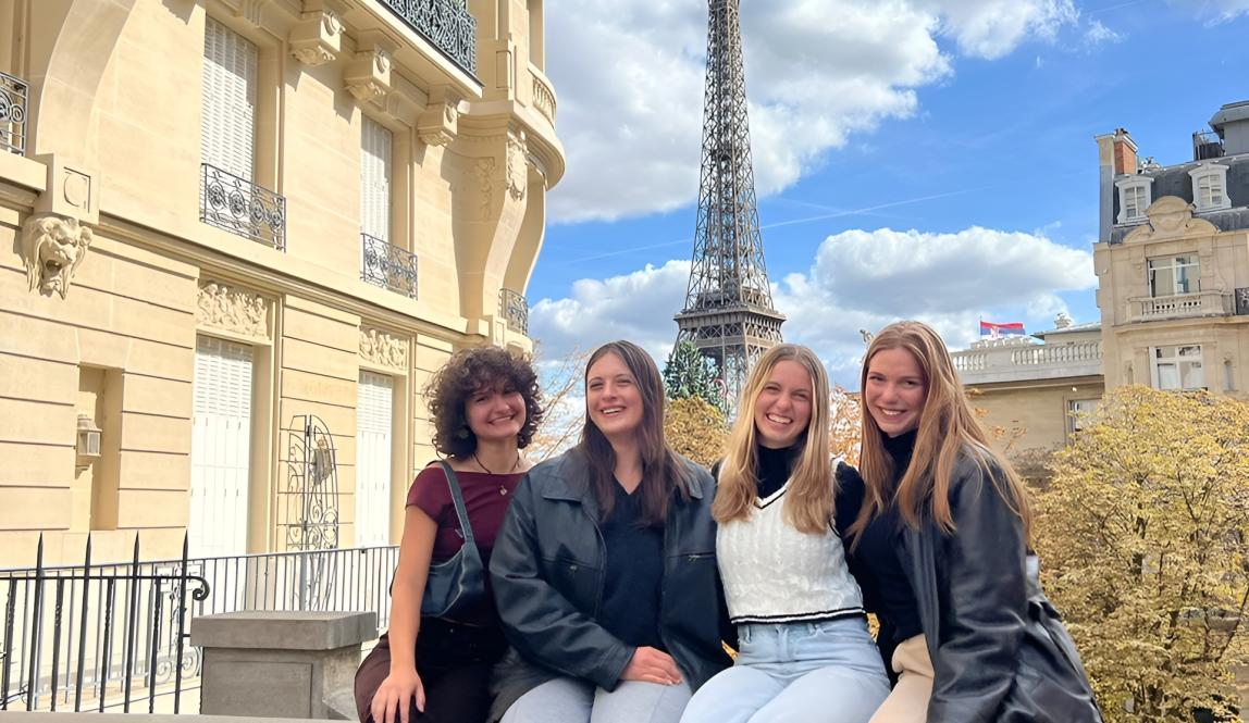 Four students at viewpoint in Nice, France - posing with city and ocean behind them 