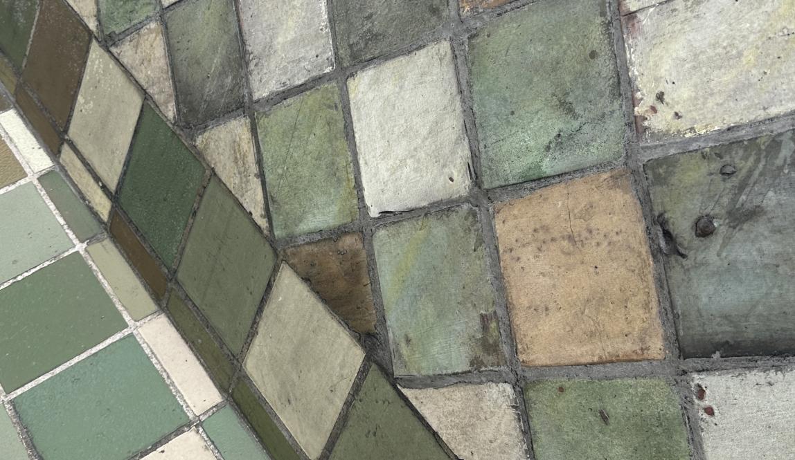 An up-close shot of green- and brown- colored tiles atop the roof of a church.